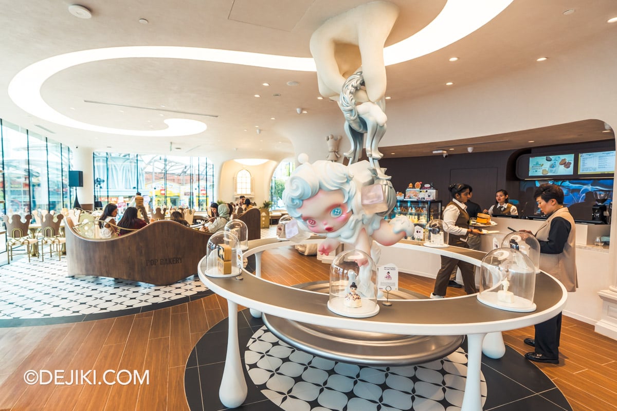 POP BAKERY Singapore at Resorts World Sentosa - Cafe Design with Peranakan Tiles and Skullpanda Sculpture SKULLPANDA sculpture above the central bell jar display at POP BAKERY, over Peranakan patterned floor tiles